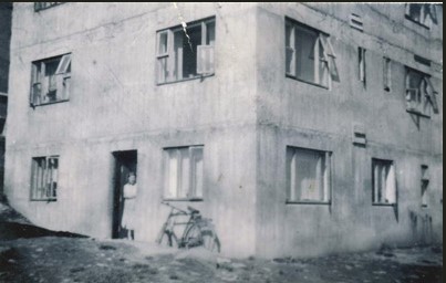 Mamma í dyrunum á kjallaraíbúðinni á Hvanneyrarbraut 62. Undir svefnherbergisglugganum er hjólið hans pabba.